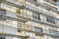Scaffolding near a new house, building exterior, construction and repair industry, white wall and window, yellow pipe Royalty Free Stock Photo