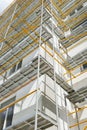 Scaffolding near a new house, building exterior, construction and repair industry, white wall and window, yellow pipe Royalty Free Stock Photo