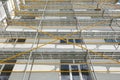 Scaffolding near a new house, building exterior, construction and repair industry, white wall and window, yellow pipe