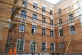 Scaffolding next to the outer wall of a four-story building. Repair and restoration of city houses. Plastering and painting of