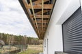 Scaffolding with three rows of wooden battens for attaching the PVC soffit, visible cables for lighting.