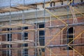 Scaffolds installed near the multi-storey brick building under constructio