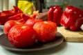 Scalded tomatoes, peeled on a plate, peppers on a wooden board