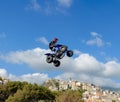 The freestyle Quad bike pilot makes a jump with a high jump with a trick.