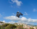 The freestyle Quad bike pilot makes a jump with a high jump with a trick.