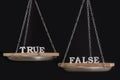Scales with truth and false. Balance on black background close up Royalty Free Stock Photo
