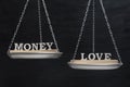 Scales with words MONEY and LOVE. Concept of balance. Scales on black background close up Royalty Free Stock Photo
