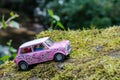 Scalextric Morris Mini Cooper 'Twiggy Flower Power' pink model car in a nature scene, on a mossy sto