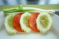 Scallion, Slices of cucumbers and tomatoes on edge of plate. Royalty Free Stock Photo