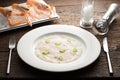 Scallops carpaccio served with chili, langoustines on a white plate and wooden rustic brown table with dinner settings. Close up Royalty Free Stock Photo