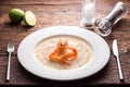 Scallops carpaccio served with langoustines on a white plate and wooden rustic brown table with dinner settings. Close up