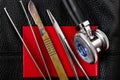 Scalpel tweezers needle holder stethoscope on red document black background leather texture