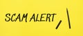scam alert sign with black marker on a yellow background. With copy space ready for your text Royalty Free Stock Photo