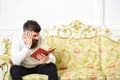 Scandalous bestseller concept. Guy reading book with attention. Man with beard and mustache sits on baroque style sofa Royalty Free Stock Photo