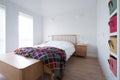 Scandi style bedroom interior with wooden bedroom furniture, white painted walls, white bedding and colourful blanket. Royalty Free Stock Photo