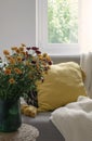 Scandinavian autumn inspired home decor -Closeup of mums flowers bouquet, cozy Living room, Sofa Cushion, knitted plaid