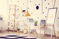 Scandinavian baby room with small wooden desk with chair, cute posters and yellow accents