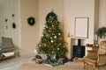 Scandinavian beige Christmas interior with decorated Christmas tree. Fireplace with armchair, wreath on the wall and gifts under