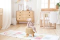 Scandinavian children`s room: a basket for toys, a plush rabbit sitting on a chair, a cradle for a baby bed. Modern interior of a Royalty Free Stock Photo