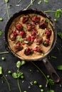 Scandinavian comfort food. Homemade meatballs in creamy gravy with red berry sause in cast iron pan with raw cilantro on black