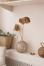 Scandinavian decor as a decoration in the house. Dried hydrangea flowers in a vase, eucalyptus branches in a wicker basket on a