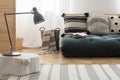 Scandinavian futon with patterned pillows on white wall and parquet on the floor, real photo