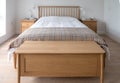 Scandinavian inspired, minimalist bedroom interior showing wooden bedroom furniture, white walls and bedding and woollen blanket