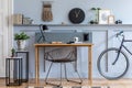 Scandinavian interior design of open space with wooden desk, modern chair, wood paneling with shelf, plant, carpet, bicycle.