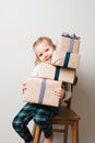 Scandinavian minimalism christmas and new year concept with kid - little girl with stack of gift box on a chair in room