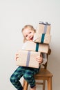 Scandinavian minimalism christmas and new year concept with kid - little girl with stack of gift box on a chair in room Royalty Free Stock Photo