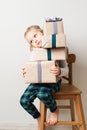 Scandinavian minimalism christmas and new year concept with kid - little girl with stack of gift box on a chair in room Royalty Free Stock Photo