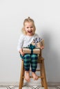 Scandinavian minimalism christmas and new year concept with kid - little girl with stack of gift box on a chair in room Royalty Free Stock Photo