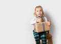 Scandinavian minimalism christmas and new year concept with kid - little girl with stack of gift box on a chair in room, white Royalty Free Stock Photo