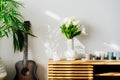 Scandinavian Minimalist home interior details - bouquet of white tulip flowers in vase, candles, Buddha statuette on
