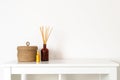 Scandinavian nordic hygge style, home interior - scent aroma diffuser with wooden sticks, perfume, small straw basket, white shelf