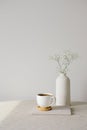 Scandinavian, nordic style home interior decoration. Cup of coffee and vase of flower on linen fabric on table. White wall on