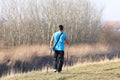 Scandinavian nordic walking. A man in sports clothes stroll through the spring s grass in the rays of sunlight. Healthy lifestyle