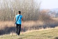 Scandinavian nordic walking. A man in sports clothes stroll through the spring s grass in the rays of sunlight. Healthy lifestyle