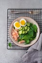 Scandinavian salad with smoked pink salmon, spinach, cucumber and chicken egg in gray ceramic dish. Top view Royalty Free Stock Photo