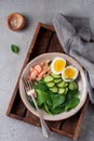 Scandinavian salad with smoked pink salmon, spinach, cucumber and chicken egg in gray ceramic dish. Top view Royalty Free Stock Photo