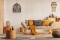 Scandinavian sofa with pillows and dark yellow blanket in bright living room interior with black chandelier Royalty Free Stock Photo