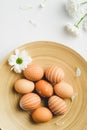 Scandinavian style easter eggs in plate and spring flowers on white background. Flat lay composition, top view. Simple, nordic