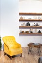 Scandinavian style interior living room. Yellow armchair, wooden shelves, table