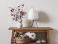 Scandinavian style interior - paper lamp, cranberry branches in a ceramic vase, basket with blankets on an oak bench in the living
