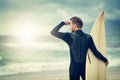 Scanning the sea for a perfect break. a laid-back young surfer watching the waves while holding his surfboard at the Royalty Free Stock Photo