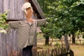 A scarecrow in old clothes, a fragment of a hut and a tree in the background