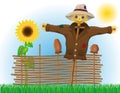 Scarecrow straw in a coat and hat with fence and sunflowers