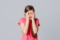 Scared anxious young girl amazed shocked hands cover face, wear in casual pink t shirt, standing over gray background. Young Royalty Free Stock Photo