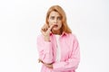 Scared and anxious young woman biting finger, looking worried at camera, standing over white background Royalty Free Stock Photo