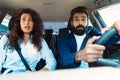 Scared arab couple looking at road with shocked expression, having risk of traffic accident driving car and braking hard Royalty Free Stock Photo